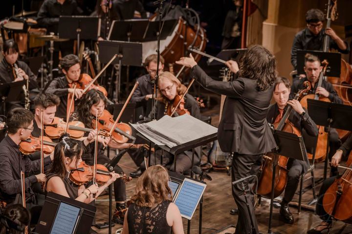 The conductor leading the orchestra, seen from above