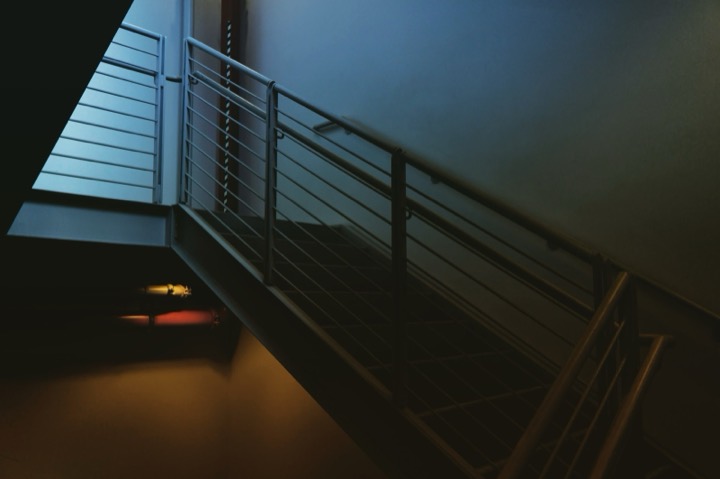 A dark stairwell lit by a single warm lamp