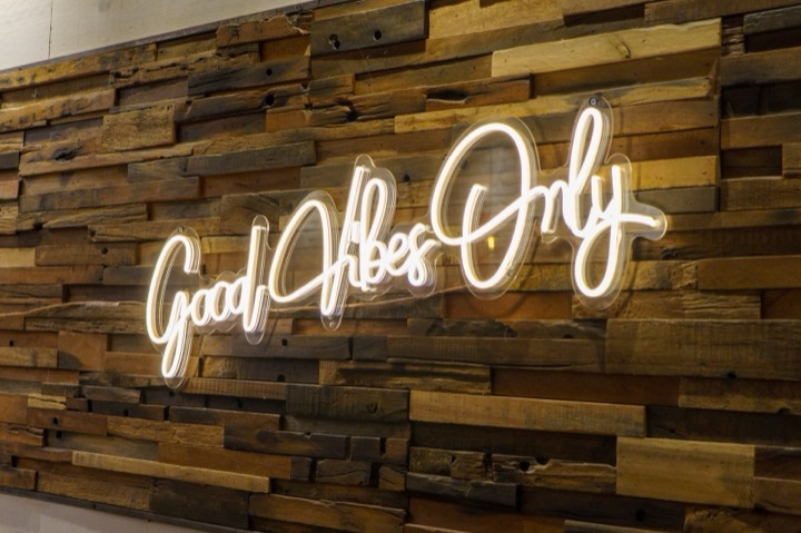 A neon Good Vibes Only sign on a reclaimed-wood wall