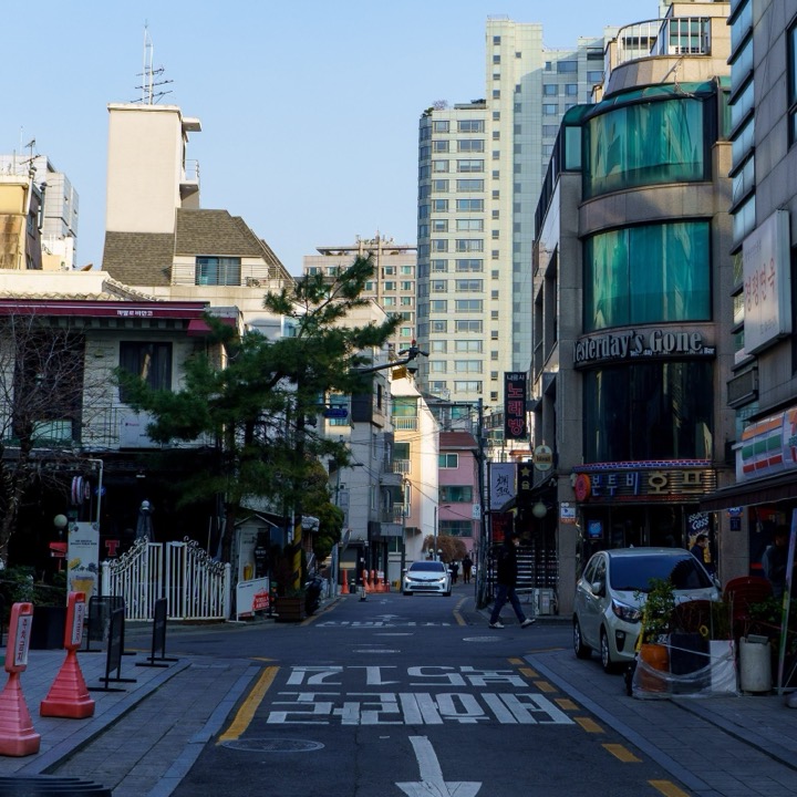 A quiet street in Seoul with apartment towers behind