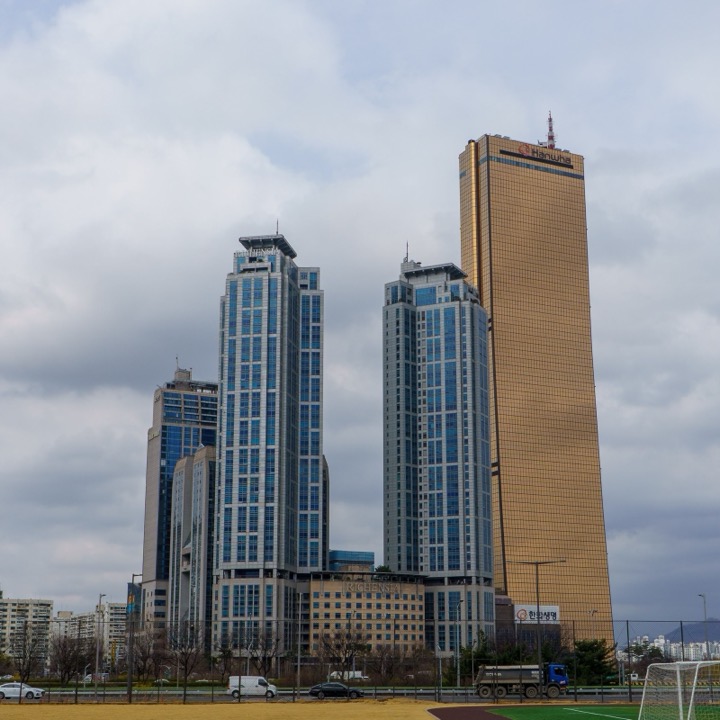 Glass skyscrapers, including a gold tower, under a cloudy sky