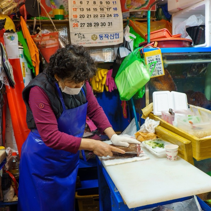 A market vendor slicing fish at a stall