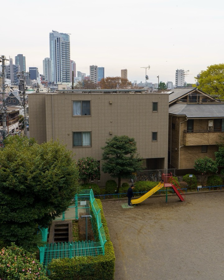A small playground between apartment buildings, with a skyline behind