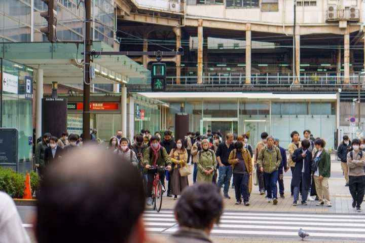 A crowd waiting at a crosswalk outside a train station
