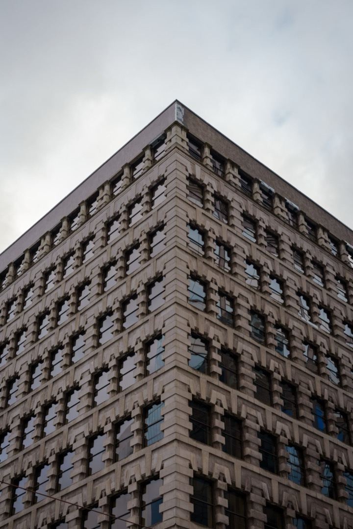 The corner of a brick building rising into a gray sky